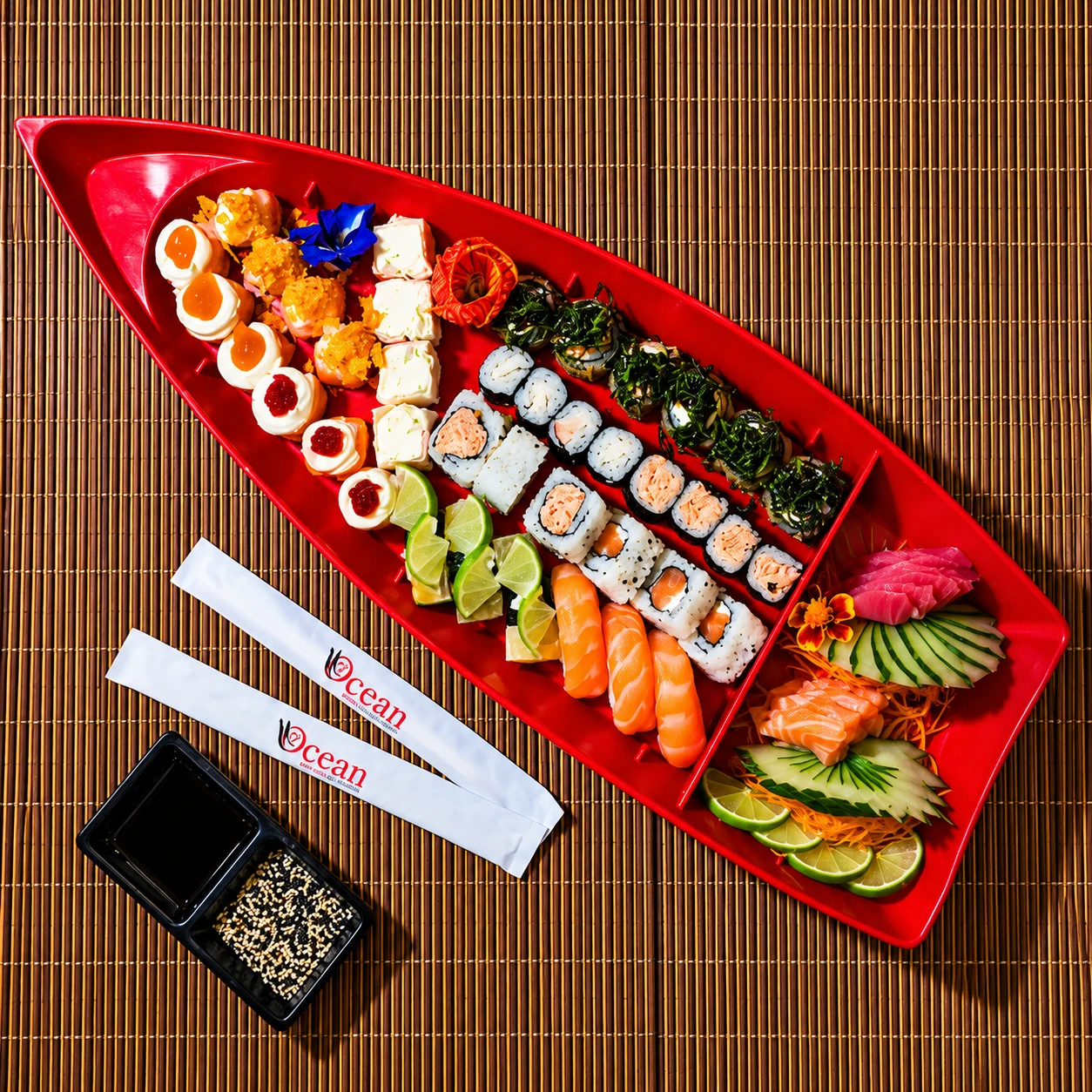 Barco vermelho de sushi Ocean com peças variadas sobre esteira de bambu